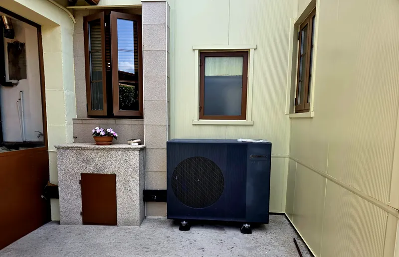 Bomba de calor aerotérmica exterior instalada en un patio de vivienda