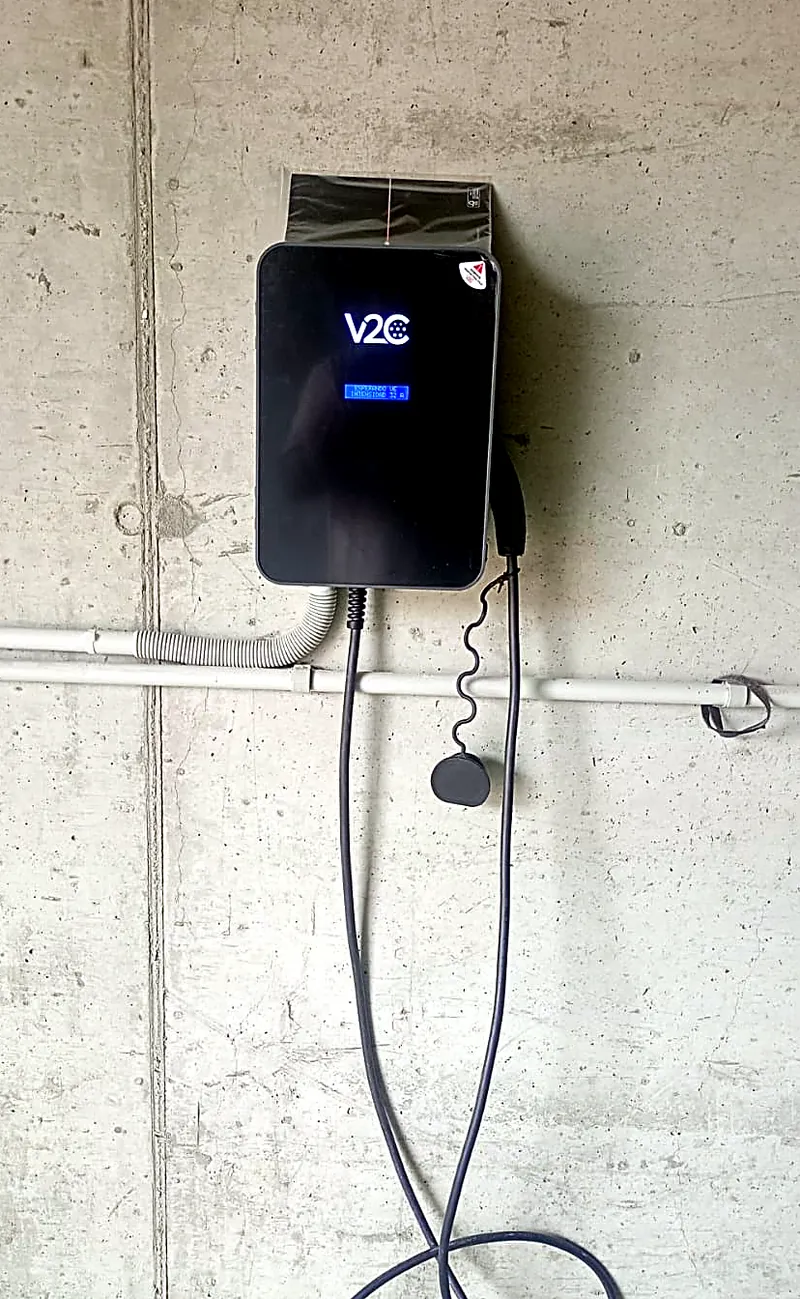 Cargador de vehículo eléctrico sobre pared de hormigón con canalización