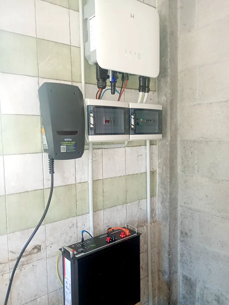 Inversor, cuadros de protección, cargador de coche eléctrico y batería instalados en una pared