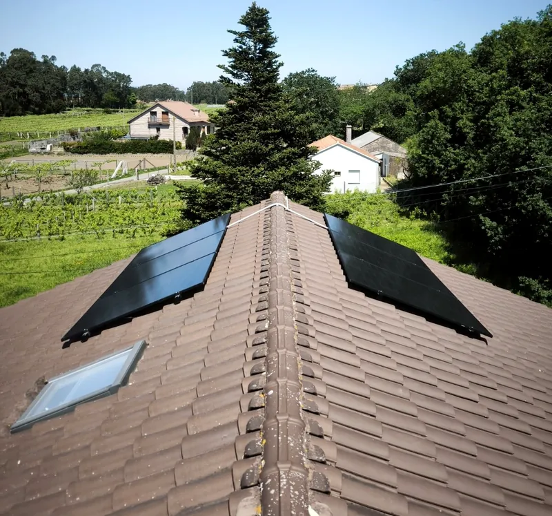 Paneles solares a ambos lados de la cumbrera junto a un lucernario, con viñedos de fondo