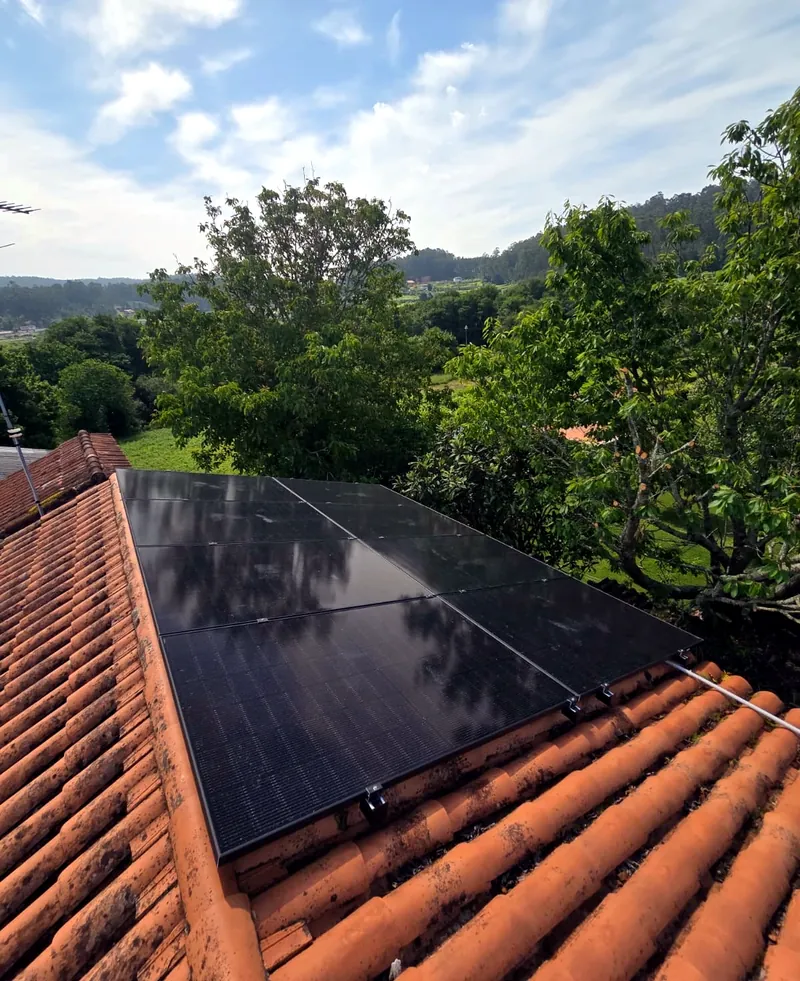Paneles solares sobre tejado de teja rodeado de árboles