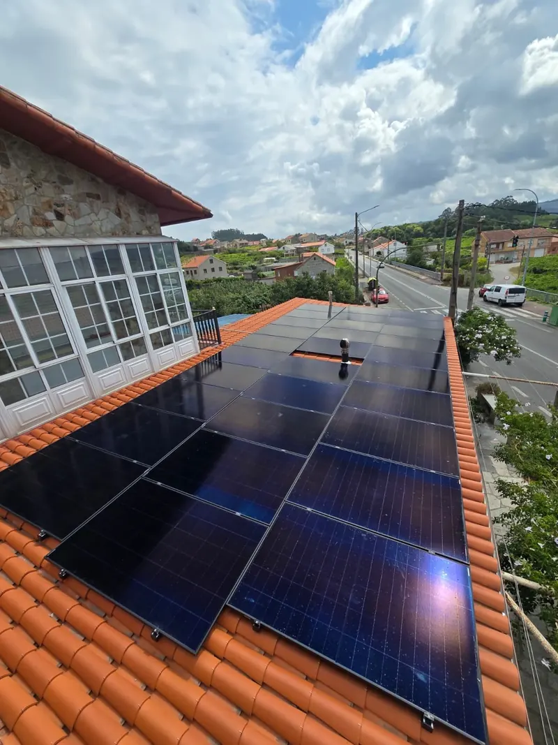 Paneles solares sobre el tejado de una vivienda con galería acristalada