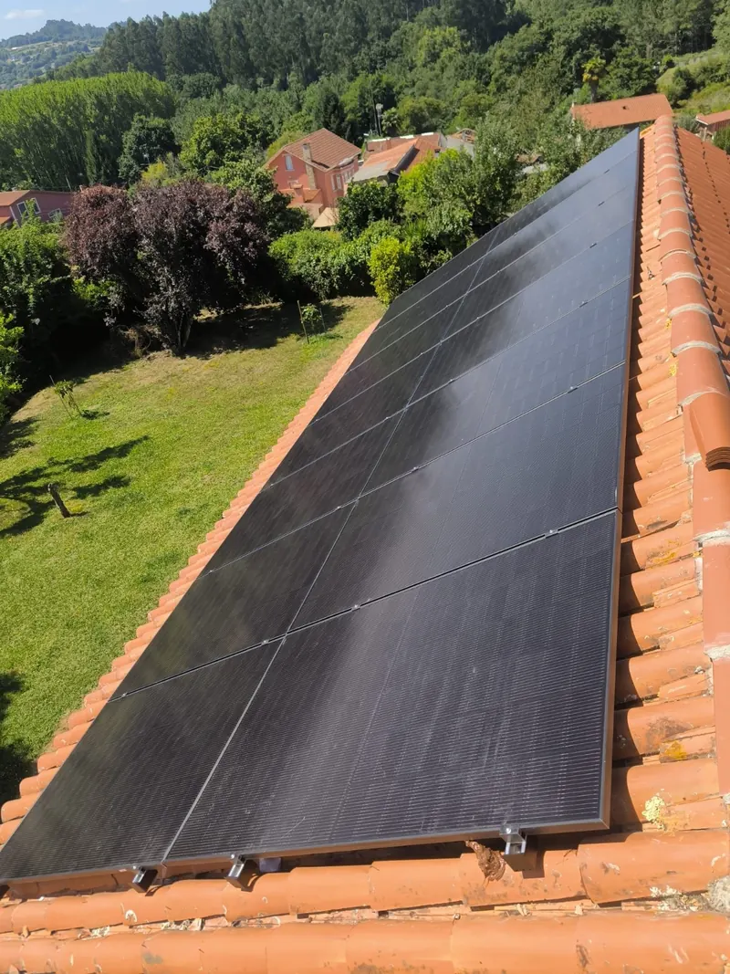 Vista aérea de paneles solares sobre el tejado de una vivienda con jardín