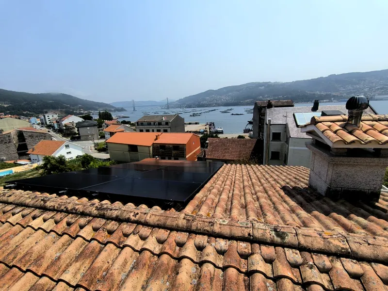 Paneles solares sobre tejado con vistas a la ría y un puente